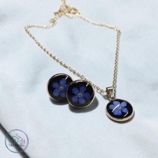 Delikatny komplet biżuterii z niezapominajkami na czarnym tle