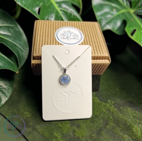 Okrągły wisiorek z niezapominajką na mlecznobiałym tle