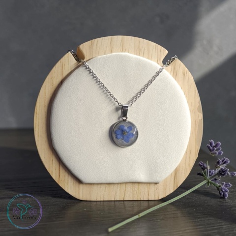 Okrągły wisiorek z niezapominajką na mlecznobiałym tle