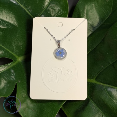 Okrągły wisiorek z niezapominajką na mlecznobiałym tle