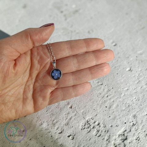 Okrągły wisiorek z niezapominajką na czarnym tle