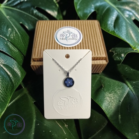 Okrągły wisiorek z niezapominajką na czarnym tle